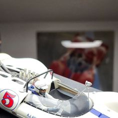 a close up of a toy race car on a table with a man in the background