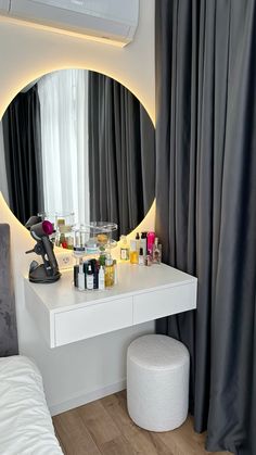 a white table with bottles and candles on it in front of a large round mirror