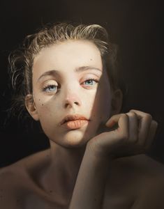 a woman with freckled hair and blue eyes poses for a photo in front of a black background