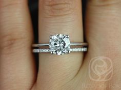 a woman's hand with a diamond ring on top of her finger and the engagement band