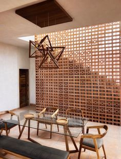 a dining room table with four chairs and a bench in front of a wooden screen