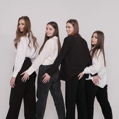 three women in black pants and white shirts posing for the camera with their hands on their hips