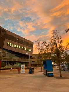 the exterior of a stadium with trees in front of it and a sky filled with clouds