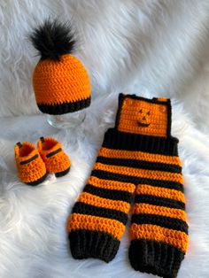 an orange and black knitted hat, mittens and booties