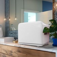 a white refrigerator sitting on top of a counter next to a blue potted plant