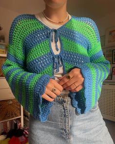 a woman wearing a green and blue striped sweater standing in front of a bookcase