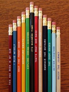 several pencils are lined up next to each other on a wooden table with writing on them