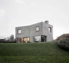 the house is made out of concrete and has large windows on each side of it