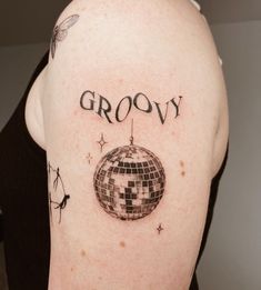 a man with a disco ball tattoo on his arm and the word grooy written in black ink