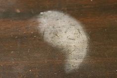 the shadow of a person on a table with wood grains and white stuff around it