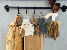 kitchen utensils hanging on the wall next to a cutting board and wooden spoons