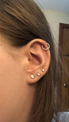 a close up of a person's ear with two piercings on it and one behind the ear