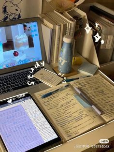 an open laptop computer sitting on top of a wooden desk next to books and papers