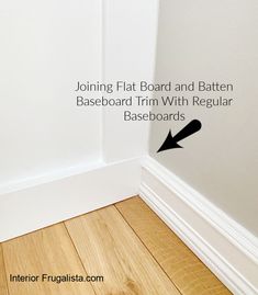 the corner of a room with white walls and wood flooring that has an arrow pointing up