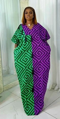 a woman standing in front of a mirror wearing a purple and green dress with geometric patterns