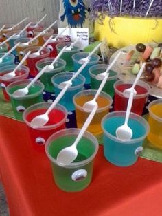 plastic cups with spoons are lined up on a table