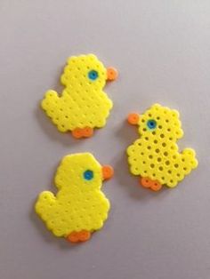 three yellow rubber ducks sitting on top of a white table next to an orange and blue object