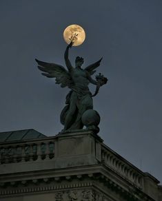 a statue on top of a building with the moon in the background