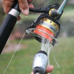 a person is spraying water from a sprinkler with a hose in their hand