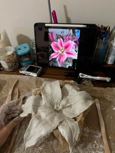 a person is working on a flower in front of a television