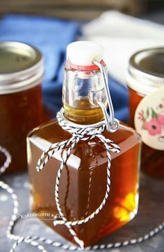 jars filled with honey sitting on top of a table next to twine ropes and tags