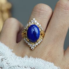 Read about our payment plans before proceeding. Elevate your elegance with the Heavenly Lapis Lazuli Ring, a stunning creation that marries the deep, celestial beauty of lapis lazuli with the timeless brilliance of white diamonds. The ring is adorned with a big natural lapis lazuli framed with natural white diamonds. Designed with a feminine antique frame, this exquisite ring is perfect for those who seek a blend of classic sophistication and modern allure. Crafted by skilled hands, this ring is available in your choice of 14K and 18K yellow gold, rose gold, and white gold. All orders come in our Tippy Taste ring box. This ring is handmade and designed in NYC. 14K or 18K solid gold Natural oval lapis lazuli, 14*10mm, approx. 5.81ct 22 Natural round diamonds. SI clarity, GH color, 0.42ct to Gold Sapphire Diamond Ring For Wedding, Exquisite Gold Rings With Halo Design, Luxury Gold Rings With Sapphire, Celestial Sapphire Ring For Formal Occasions, Gold Sapphire Halo Ring For Wedding, 14k Gold Celestial Jewelry For Formal Occasions, Celestial 14k Gold Rings For Formal Occasions, Celestial Yellow Gold Jewelry With Center Stone, Celestial 14k Gold Jewelry For Formal Occasions