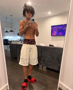 a man with dreadlocks is taking a selfie in the mirror while wearing red shoes