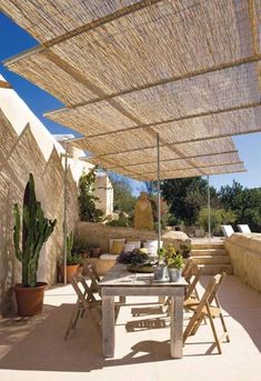 an outdoor dining area with tables, chairs and umbrellas over the table is surrounded by succulent plants