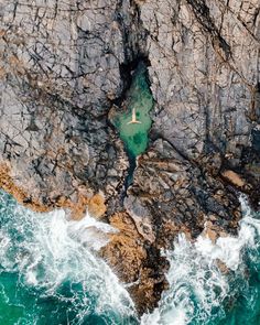 an aerial view of the ocean and rocks