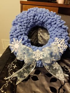 a blue knitted wreath with snowflakes on it sitting on top of a bed