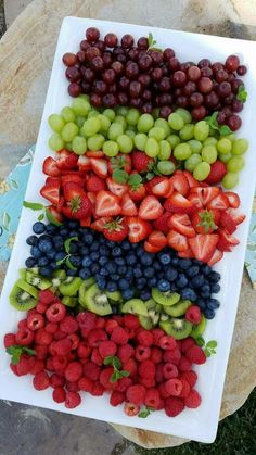 grapes, strawberries, and kiwis are arranged on a platter to be eaten