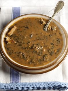 a bowl filled with soup on top of a blue and white towel next to a spoon