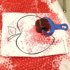 a red and white table topped with a blue pair of scissors next to a piece of paper