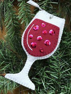 a red and white wine glass ornament hanging from a christmas tree with pink sequins