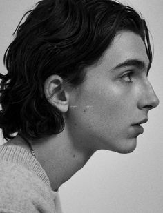 a black and white photo of a young man with curly hair looking to the side