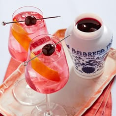 two glasses filled with pink liquid and garnished with an orange slice