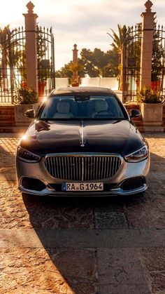 a black car parked in front of a gated area with pillars and gates behind it