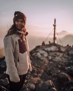 a woman standing on top of a rocky hill