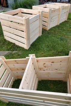 four wooden planters sitting on top of grass in the middle of a garden area