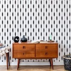 a wooden dresser sitting in front of a wall with black and white dots on it