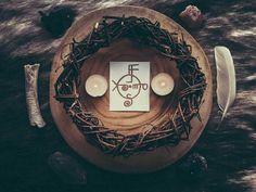 a wooden plate topped with two candles next to a bird's nest