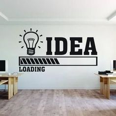 an office with desks and computer monitors on the wall that says idea loading in black