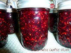 four jars filled with red liquid sitting on top of a table