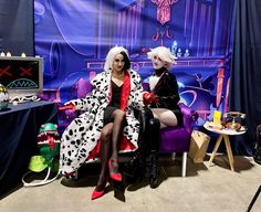 two women dressed in dalmatian costumes sitting on purple chairs