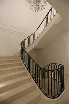 an elegant staircase with chandelier and white walls