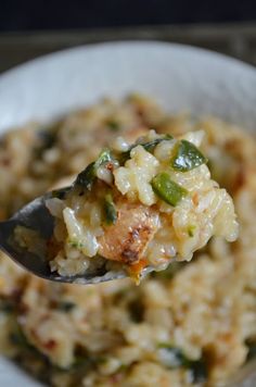 a spoon full of rice and vegetables in a white bowl