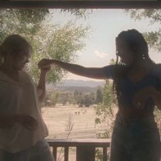 two women are standing on a porch and one is pointing her finger at the other