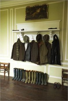 several coats and boots are hanging on the wall