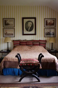 a large bed in a bedroom next to two lamps and pictures on the wall above it