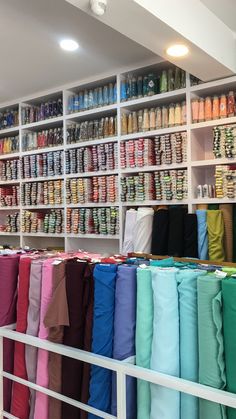 many different colored umbrellas are on display in a store with white shelving behind them